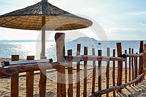 Sandy beach, sun umbrella and wooden fence. Vacation on the sea.