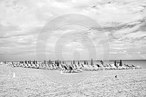 Sandy beach with sunbeds and folded, pink umbrellas