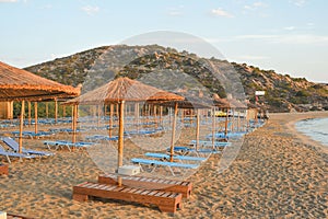 Sandy beach with sunloungers and thatched umbrellas.