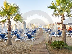 Sandy beach to sea with wooden footpath, sun beds, umbrellas, pa