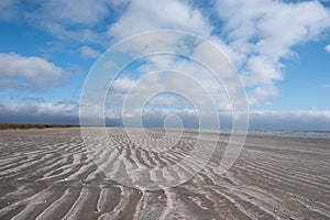 A sandy beach under a blue sky dotted with white clouds