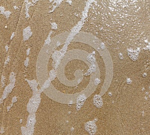 Sandy beach wet surface, top view. Sea tide waves, natural sand and water texture. Smooth sand background.