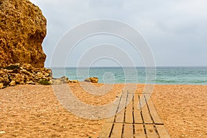 A sandy beach with wooden boardwalk ending at sea