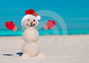 Sandy Christmas snowman in red Santa hat and mittens without sunglasses. Beach Snowman.