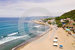 Sandy coast, buildings and blue sea with waves. San Juan, La Union, Philippines. The beaches of the Philippine Islands. Town near