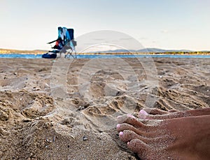 Sandy feet on lonely beach blurry background