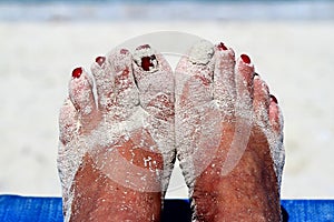 Sandy feet with painted toe nails on the beach