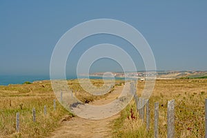 Sandy hiking trail in a field on the ciffs on the French Northe sea coast, with the city of Wiemereux in the background