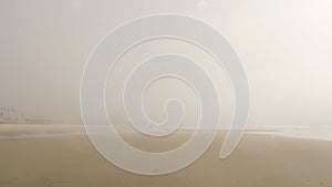 Sandy misty beach California USA. Pacific ocean coast dense fog on sea shore. Milky smog brume haze photo