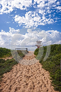 Sandy pathway to the beach patrol tower clouds