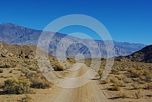 Sandy road through rocks to high mountains