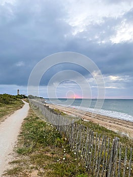 sandy roads along the ocean converging to one point, lighthouse at sunset, perspective view