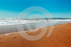 Sandy seashore. Blue waves and footprints on the yellow sand. Summer time. rest and vacation