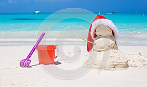 Sandy snowman with red Santa Hat and beach toys