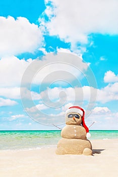 Sandy snowman in santa hat at beach. Christmas concept