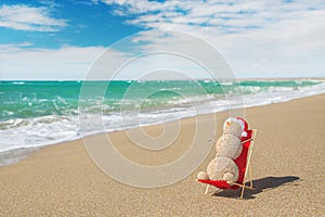 Sandy snowman in santa hat sunbathing in beach lounge.