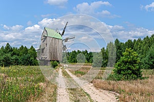 A sandy, well-trodden road leads to a mill at the edge of the forest.