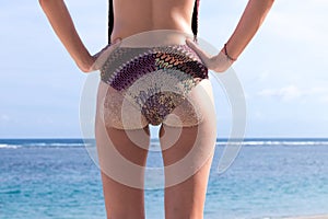 sandy woman buttocks on tropical beach of Bali island, background near ocean. Indonesia.