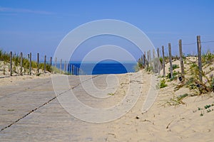 Sandy wooden path access beach on a sunny day with blue sky and waves in lacanau Atlantic coast in france