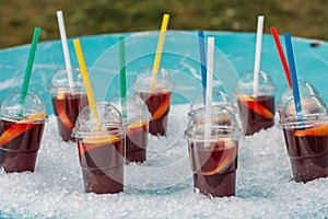 Sangria in plastic cups with straws in ice