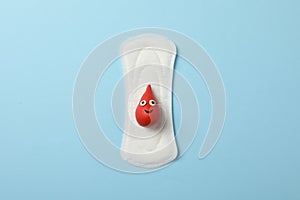 Sanitary pad with drop of blood on blue background