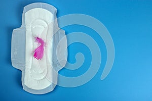 Sanitary pad, pen on blue. Personal hygiene, the concept of feminine hygiene. Critical days, blood period, menstrual cycle