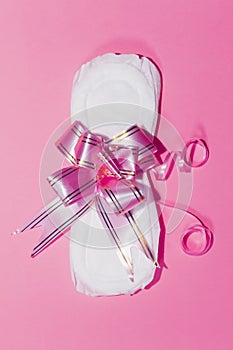 A sanitary pad tied with ribbon on the pink background