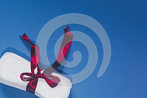 A sanitary pad tied with ribbon on the pink background