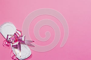 A sanitary pad tied with ribbon on the pink background