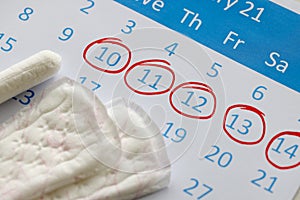 Sanitary pads and tampons are on calendar. Numbers are circled in red pen photo