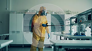 Sanitation worker disinfects a class room.