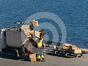 Sanitation Worker Loading Cardboard into Garbage Truck by the Sea