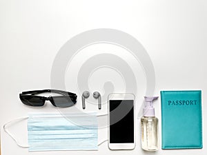 Sanitizer bottle,mask,passport,smartphone,ear buds,passport and compass isolated on white background with copy space.