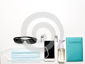 Sanitizer bottle,mask,passport,smartphone,ear buds,passport and compass isolated on white background with copy space.