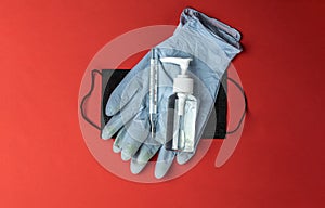 Sanitizer bottle, Medical surgical mask, lab gloves and thermometer - Virus protection equipment on red background. COVID middle