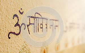 Sanskrit writing with om, aum, ohm symbol on the wall