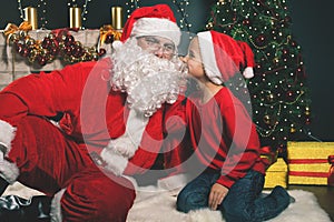 Santa and boy near the decorated Christmas tree. Wishes list