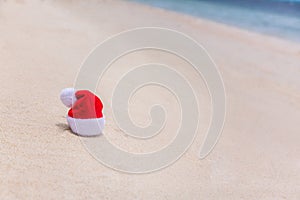 Santa Christmas hat in sand on a tropical beach. Holiday tropic summer concept