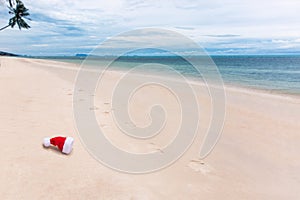 Santa Christmas hat in sand on a tropical beach. Holiday tropic summer concept. Thrown cap