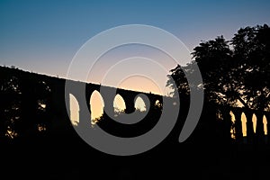 Santa Clara Aqueduct in Vila do Conde, Portugal in silhouette at sunset with blue-orange gradient sky