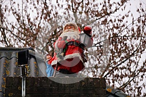 Santa Claus as a Christmas decoration on a chimney, Holidays winter time. tradition with presents and conviviality.