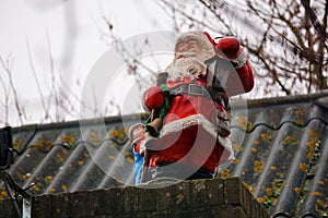 Santa Claus as a Christmas decoration on a chimney, Holidays winter time. tradition with presents and conviviality.