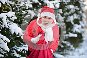 Santa Claus with a bag of gifts walk in the winter snowy mountains snow in Christmas.