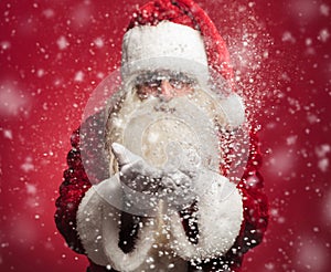 Santa claus blowing snow flakes out of his hands