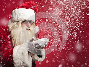 Santa claus is blowing snow flakes out of his palms