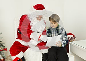 Santa Claus and a boy are reading from a paper