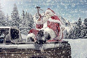 Santa Claus in a car driving to deliver some christmas presents on a sunny winter day. Blurred mountain forest background.