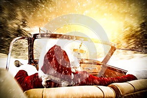 Santa claus in a car driving to deliver some christmas presents on a sunny winter day. Christmas decor on gold red background.