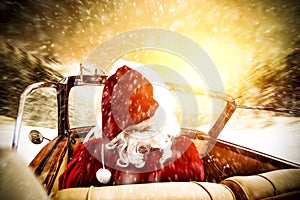 Santa claus in a car driving to deliver some christmas presents on a sunny winter day. Christmas decor on gold red background.