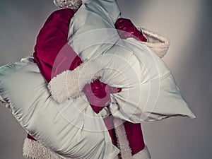 Santa Claus carries a large pillow under his arm and is going to sleep. After the holidays, good night. Conceptual image
